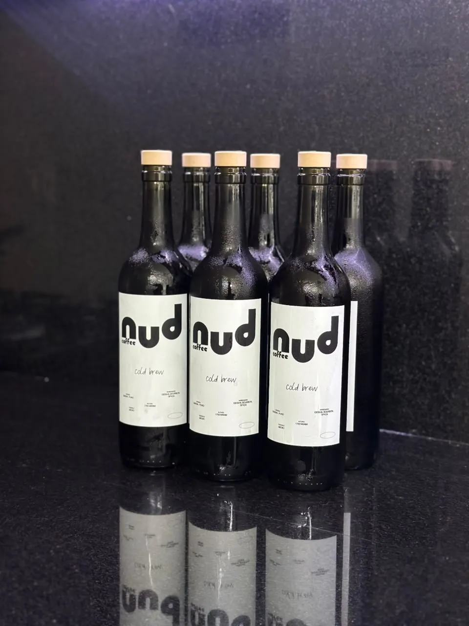 botellas de cold brew de nud coffee alineadas sobre fondo negro